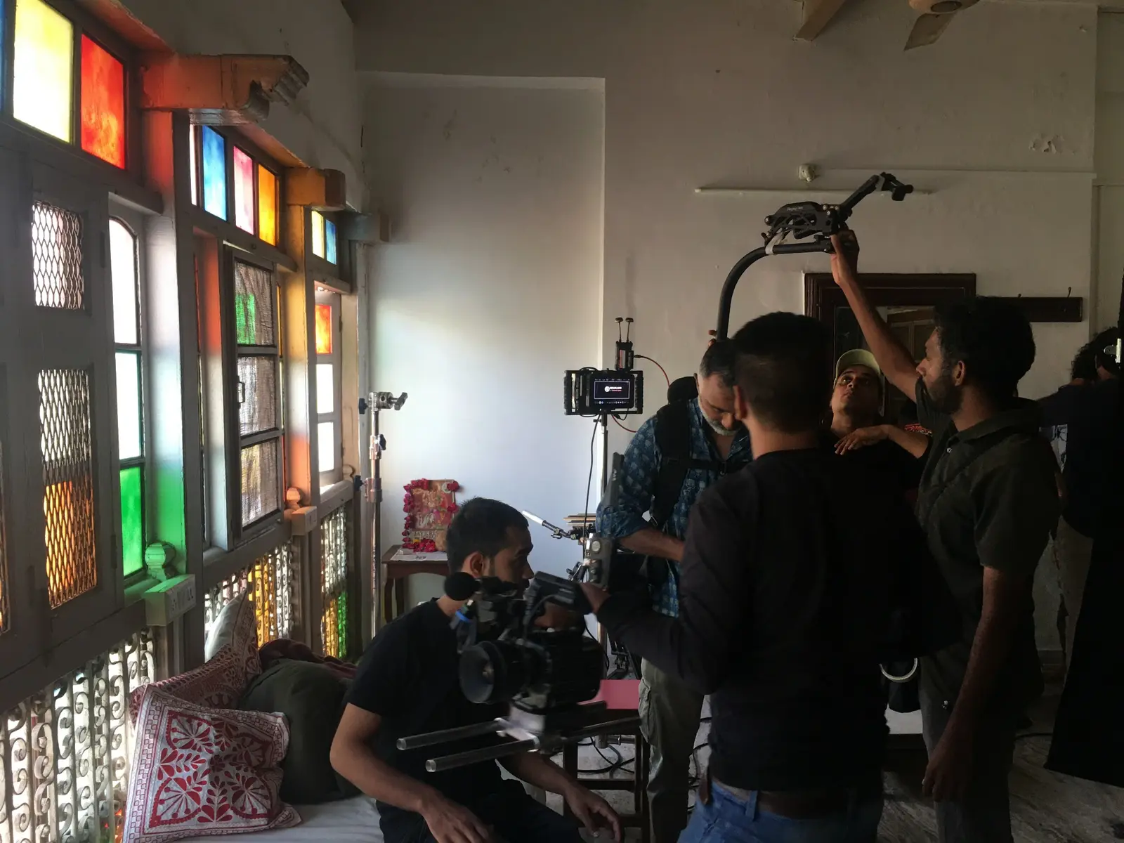 Camera crew preparing an interior shot beside coloured glass windows