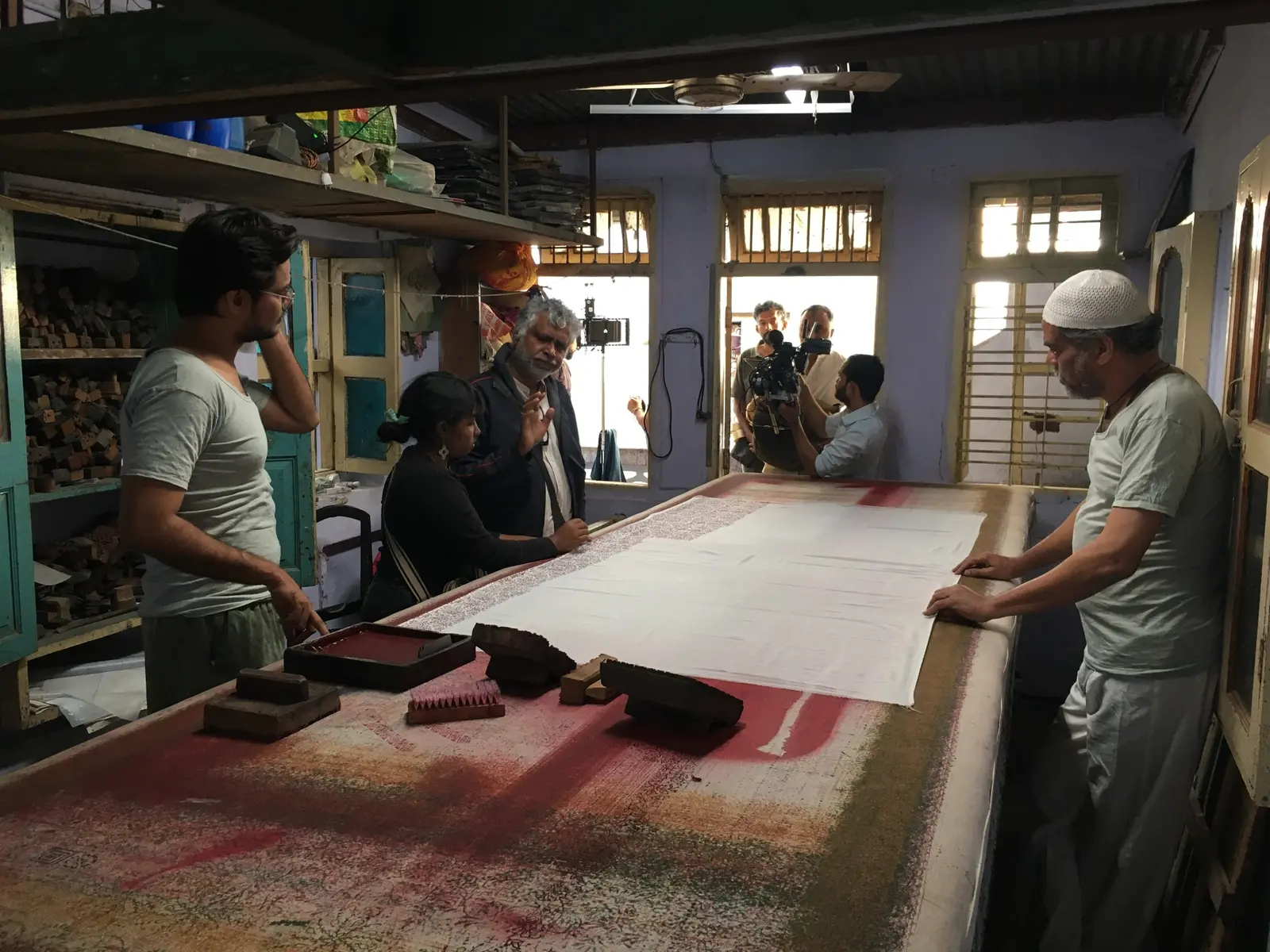 Director and crew staging a scene inside a textile workshop