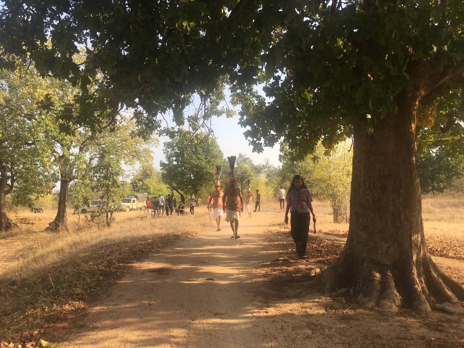 Performers and production crew walking through a wooded location