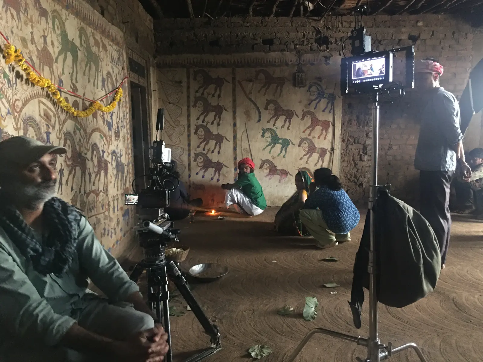 Camera and lighting crew filming performers inside a painted rural house